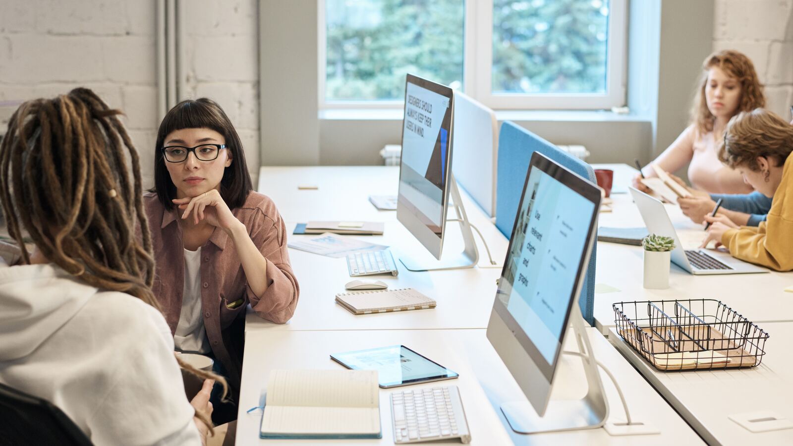Colleagues reviewing resumes and application dashboards on office monitors