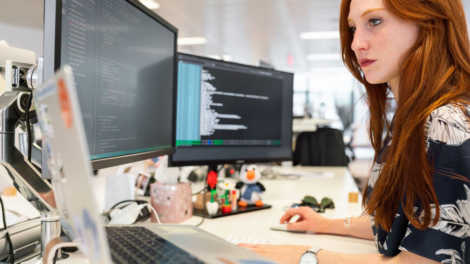 Software engineer reviewing code across multiple monitors